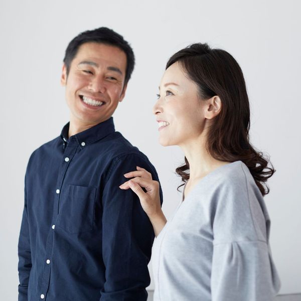 A woman with a supportive hand on a man's shoulder, both smiling and looking towards the right side of the frame. A woman with a supportive hand on a man's shoulder, both smiling and looking towards the right side of the frame.