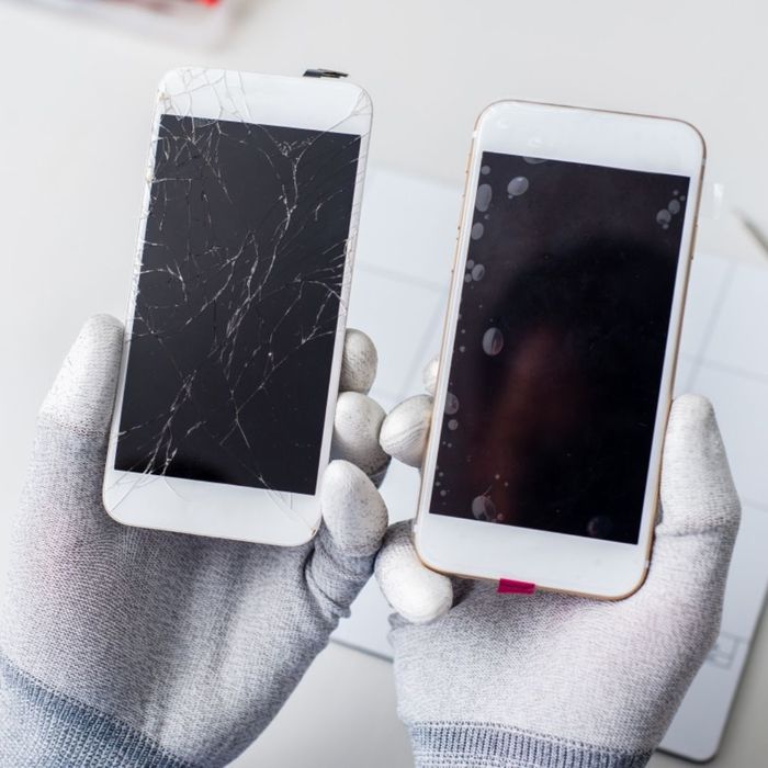 a professional repair person holding two types of broken cell phone screens