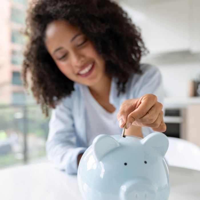 a woman putting money in a piggy bank