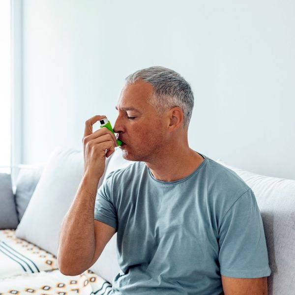 man using an inhaler. 