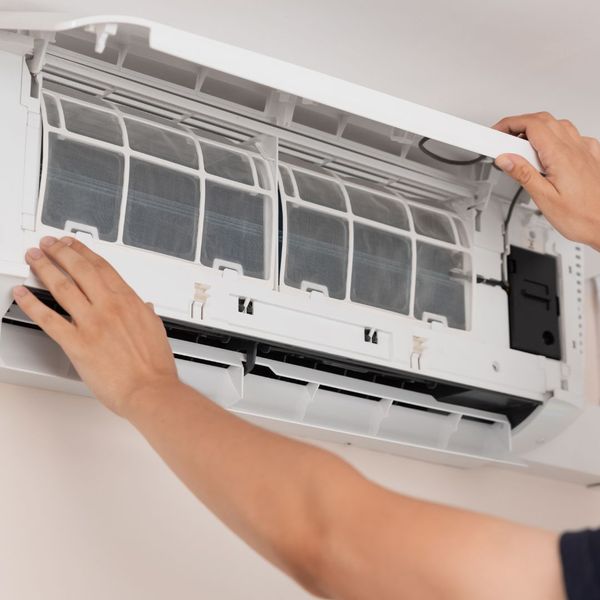 Hands adjusting air conditioner filter cover