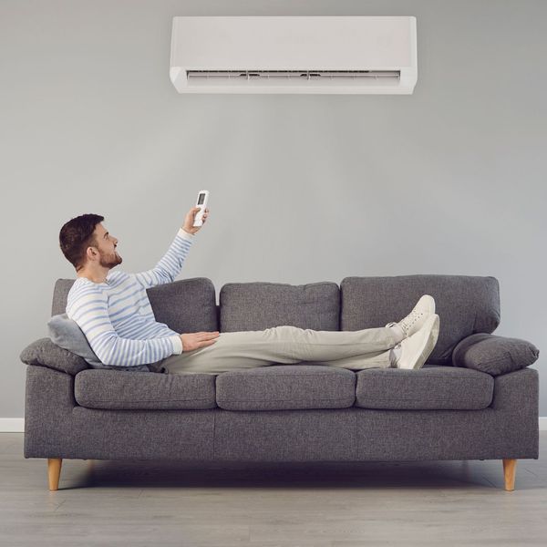 Man on couch using remote for air conditioner