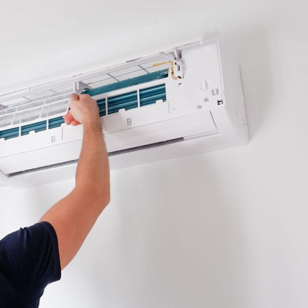 Person cleaning inside of wall-mounted air conditioner unit