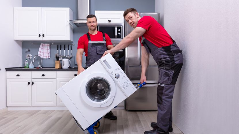 Two movers moving a washing machine. 