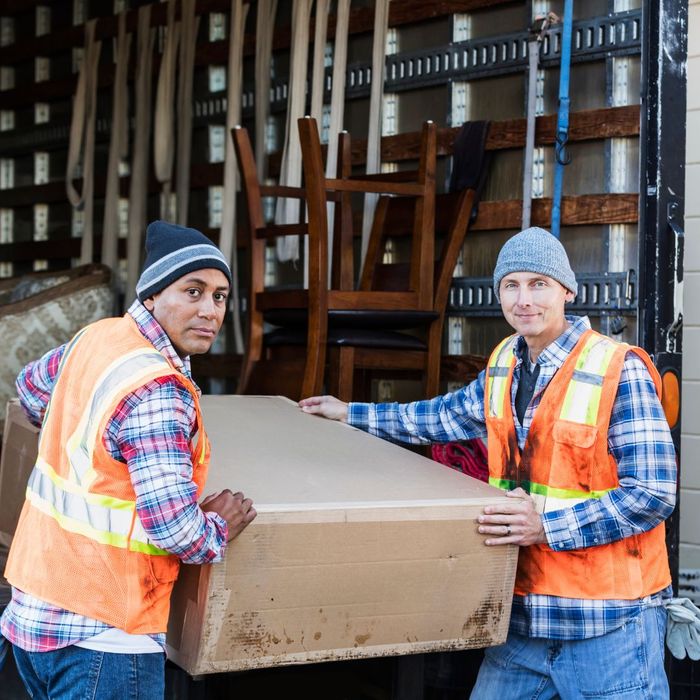 Two movers moving a large box. 