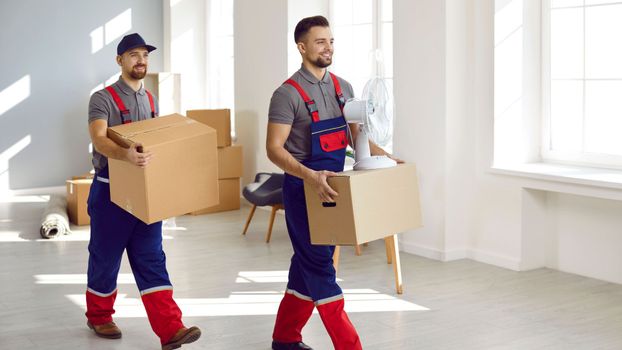 Two commercial movers carrying boxes out of an office space. 