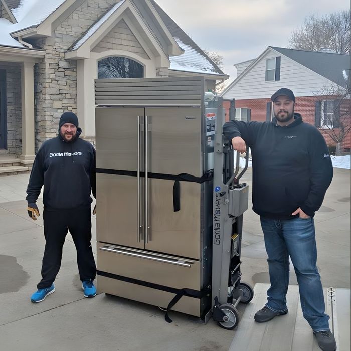 two Gorilla Movers standing next to a large fridge with snow in the background