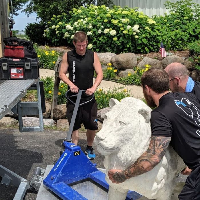 movers moving large lion stone statue