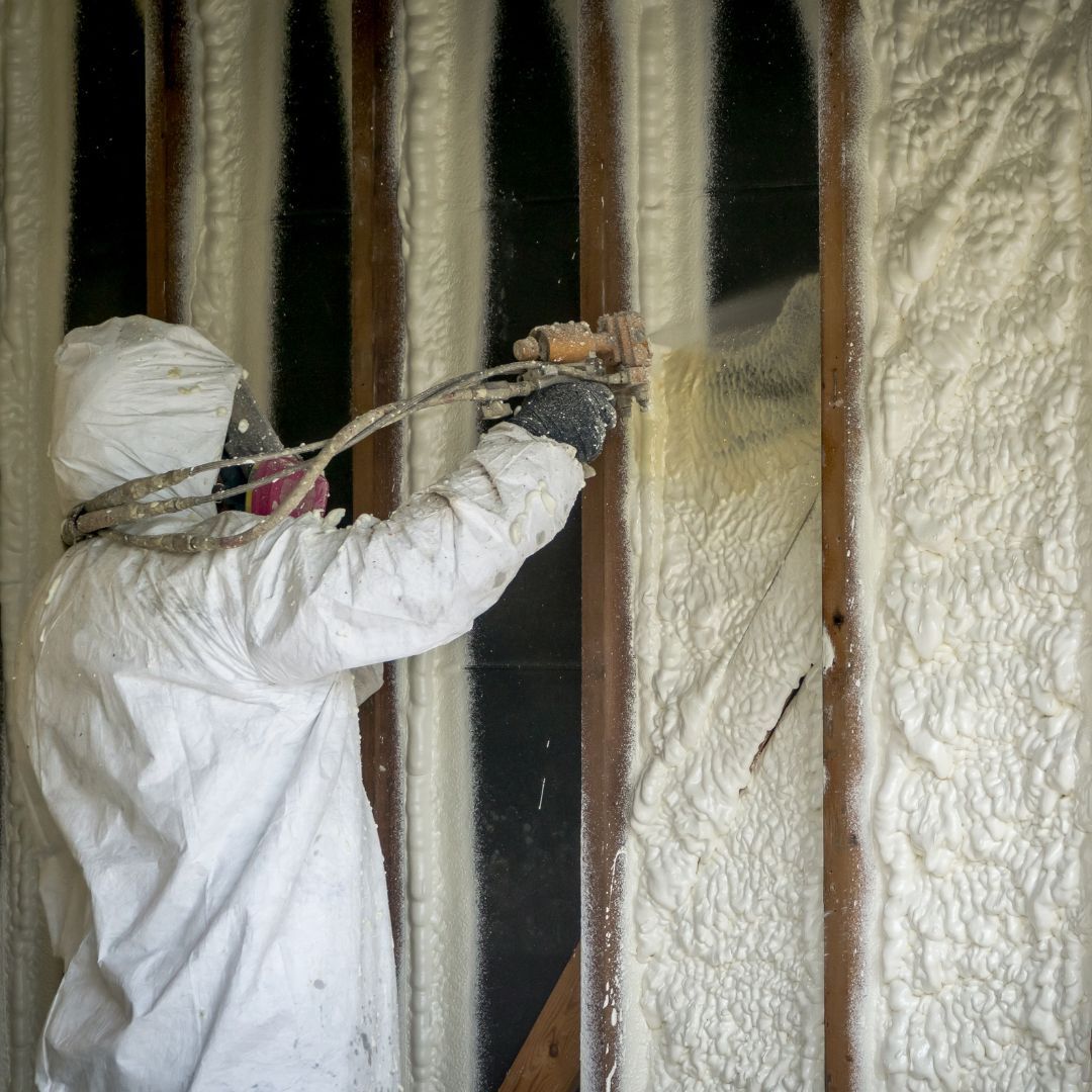 Contractor in PPE installation spray foam insulation