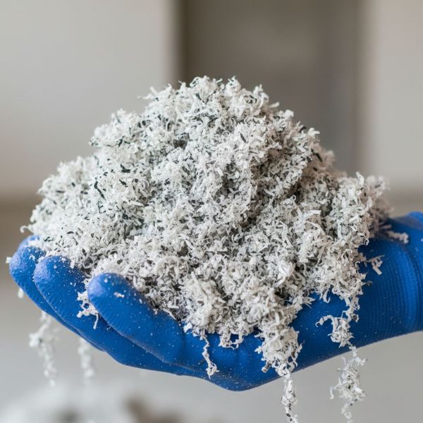 A contractor's hand holding a sample of clean, eco-friendly cellulose insulation material.