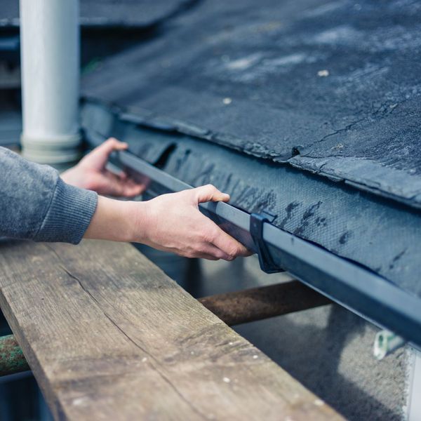 person examining roof gutter