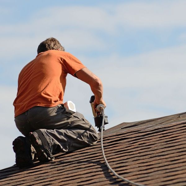a roofer nailing shingles to a roof
