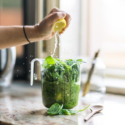 Herbs and lemon juice being squeezed into a pitcher