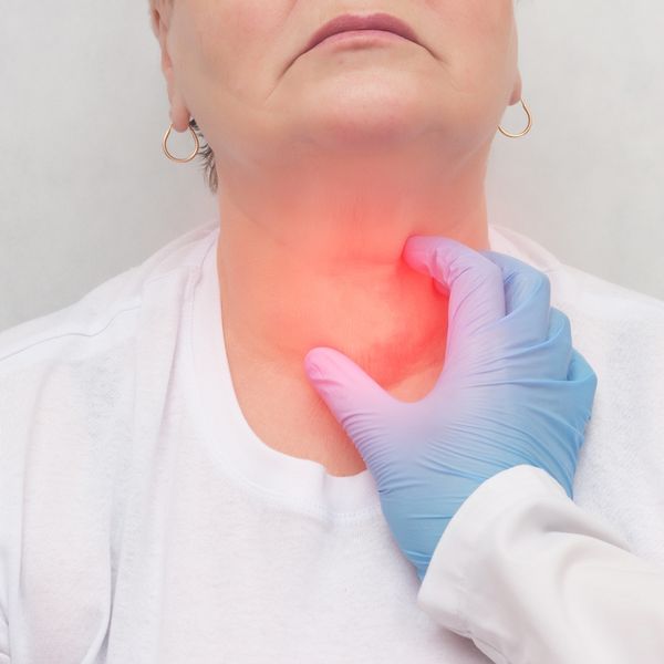 Doctor checking woman's thyroid