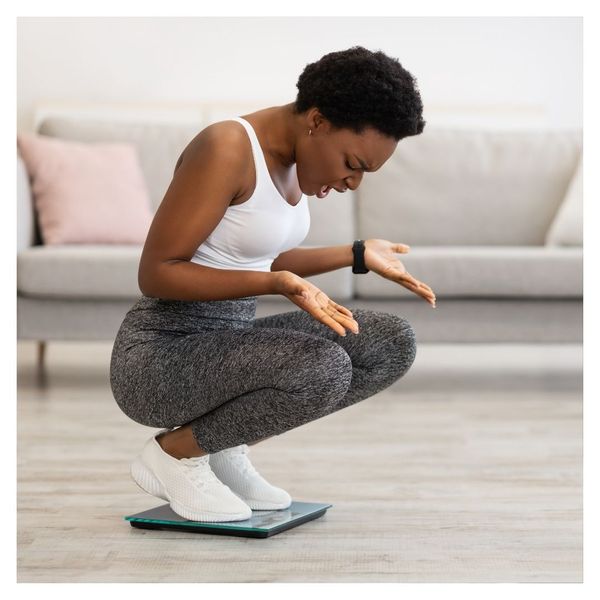 frustrated woman looking down at scale