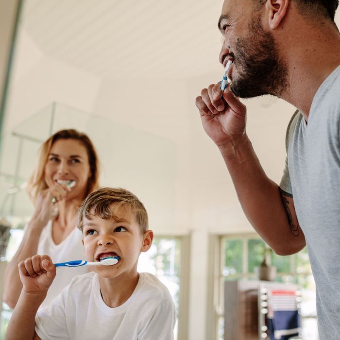 man woman and child brush teeth together How Can Routine Dental Check-Ups Save You Money 3.jpg
