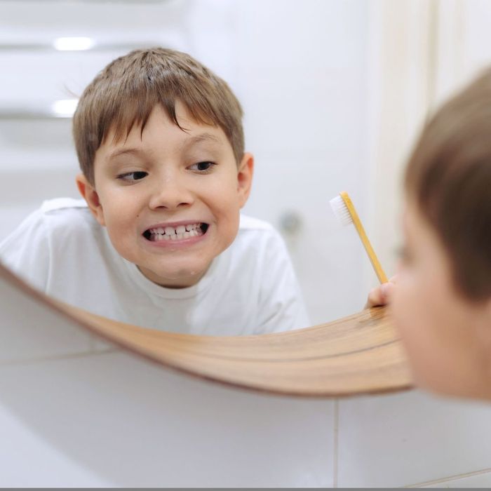boy examines teeth in bathroom mirror Common Misconceptions About Dental Care Debunked 3.jpg