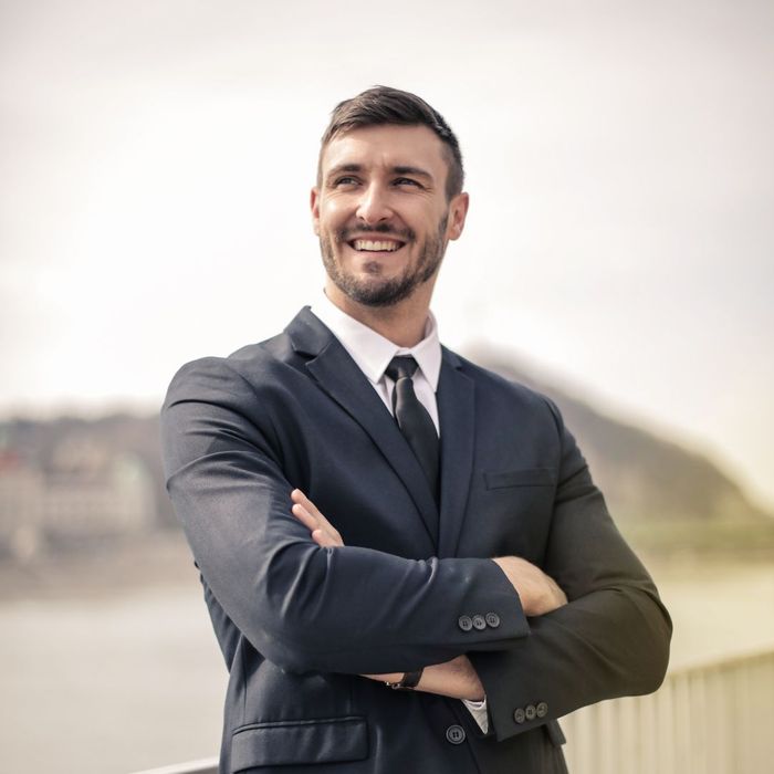 man in suit smiles with arms folded Addressing Common Myths About Dental Implants 3.jpg