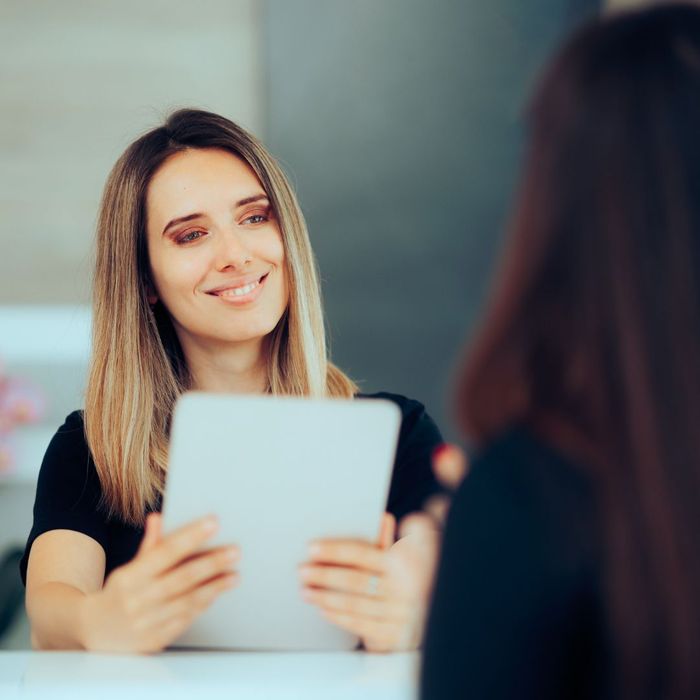 woman holds tablet sitting at table across from someone Addressing Common Myths About Dental Implants 4.jpg