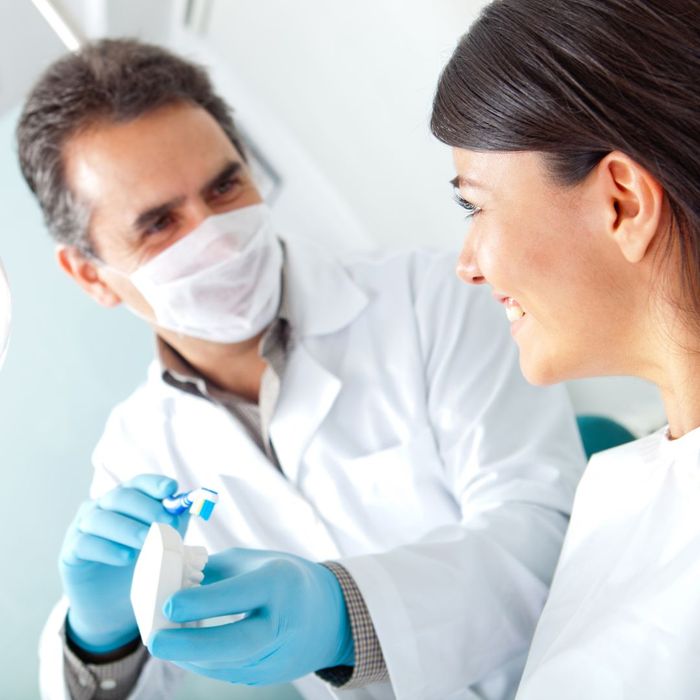 dentist wearing mask demonstrated brushing with mold of teeth How Dental Implants Can Improve Your Quality of Life 4.jpg
