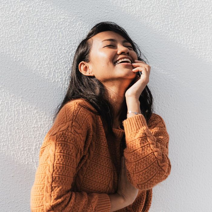 woman in sweater tilts head back and laughs How Dental Implants Can Improve Your Quality of Life 1.jpg