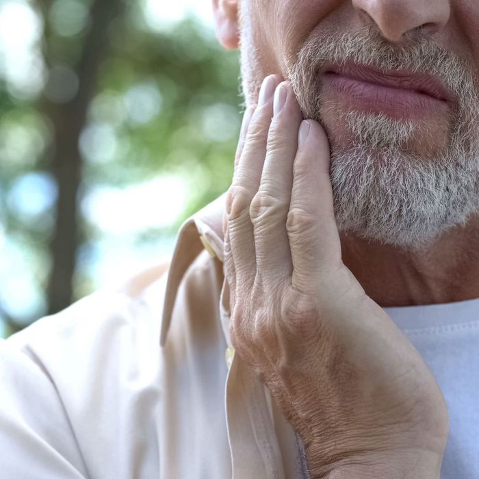 man holds tooth through cheek How Can Routine Dental Check-Ups Save You Money 2.jpg