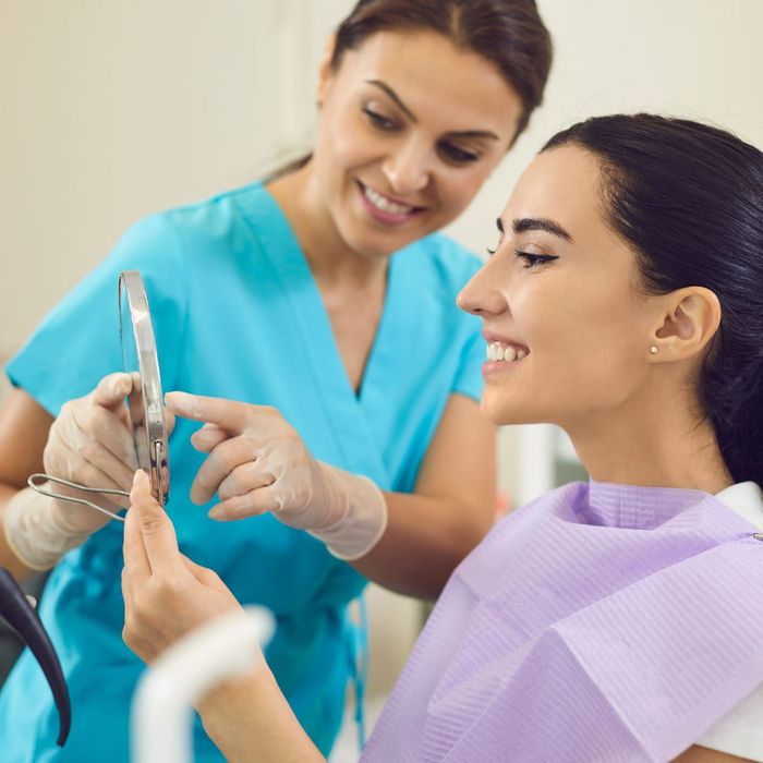 dentist and patient look at her teeth in mirror dentist and patient look at her teeth in mirror