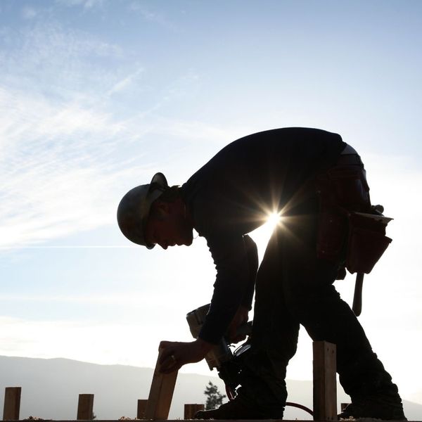 silhouette of a construction worker hunched over in the sun silhouette of a construction worker hunched over in the sun