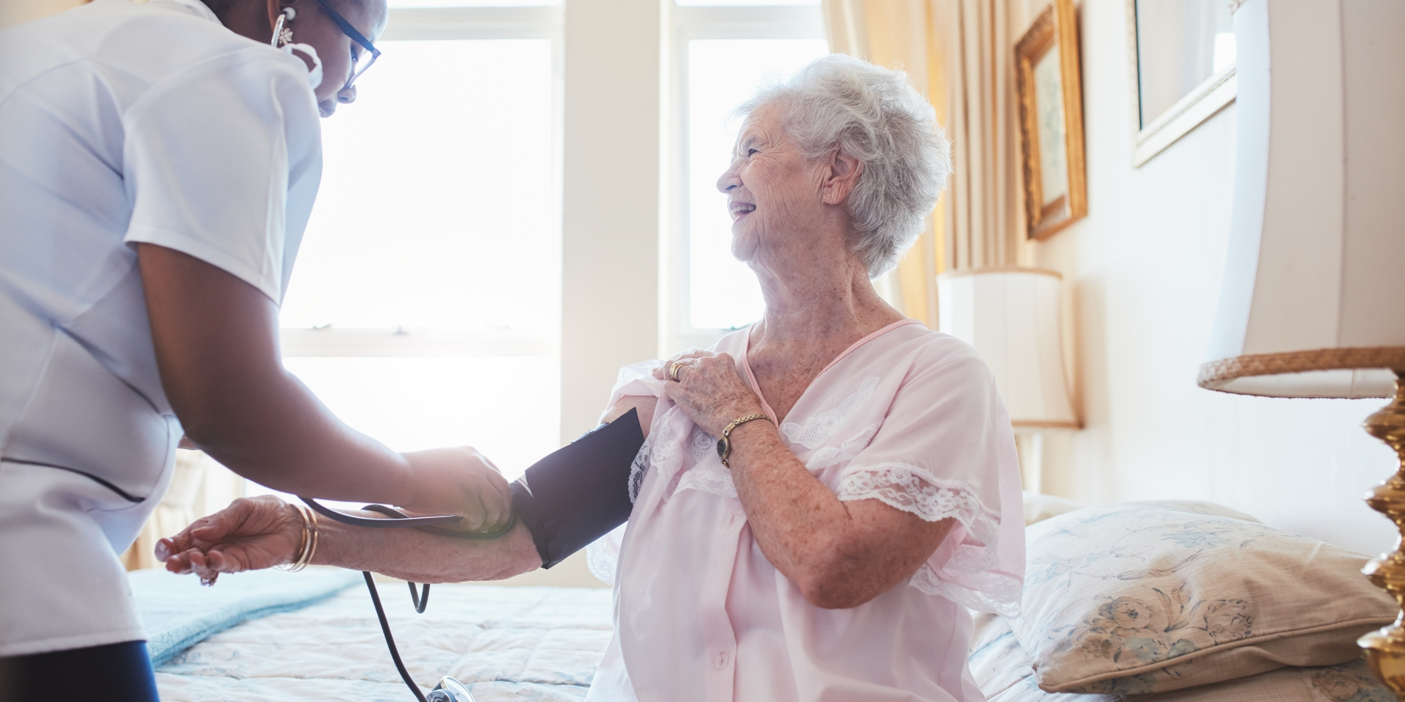 woman taking elderly persons blood pressure