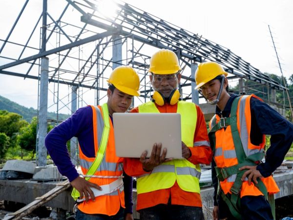 construction workers look at a computer