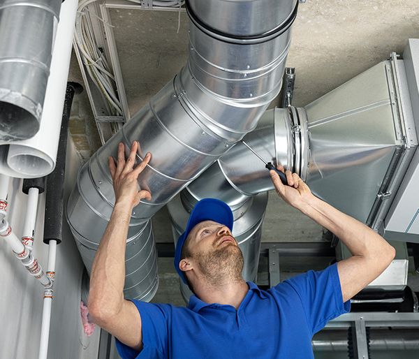 Image of a man working on a ducted heat pump