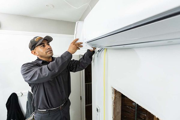 Image of a man repairing an air conditioning unit