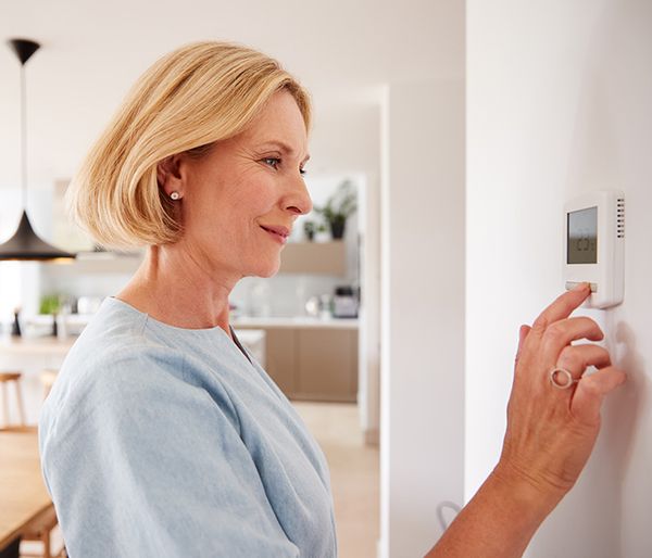 Image of a woman adjusting the thermostat in her home