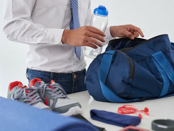 A gentleman in work clothing packing up a gym bag at home.