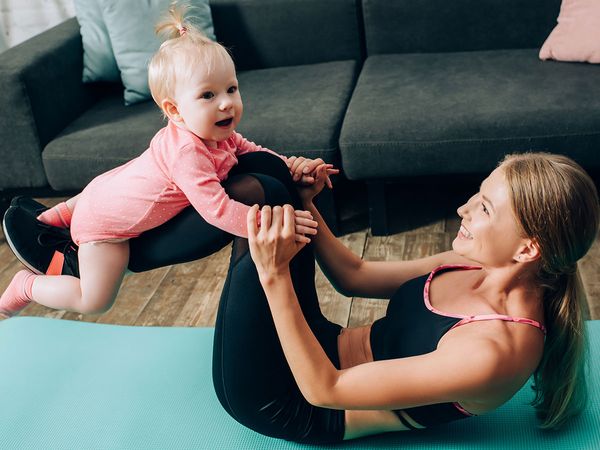 Young woman taking a break from working out at home to play with her baby.