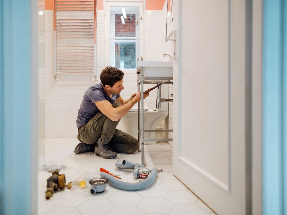 Plumber working under sink