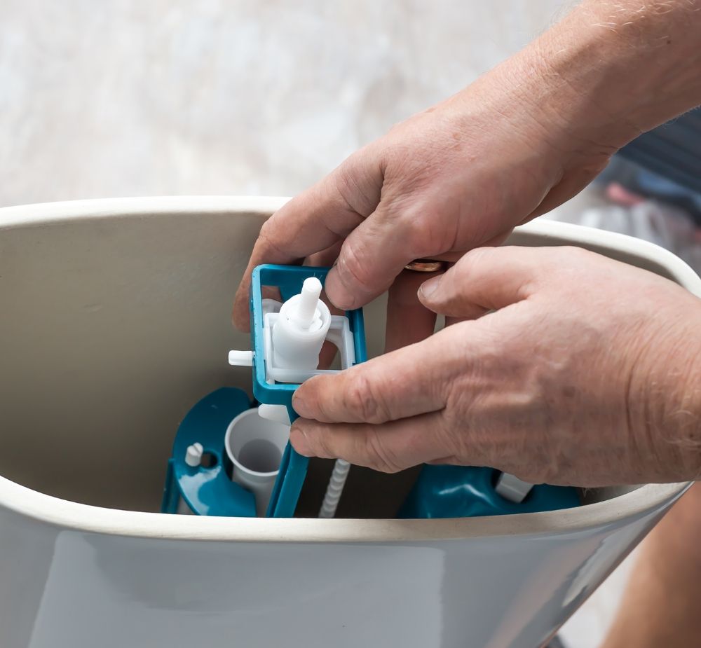 A plumber working on the parts of a toilet