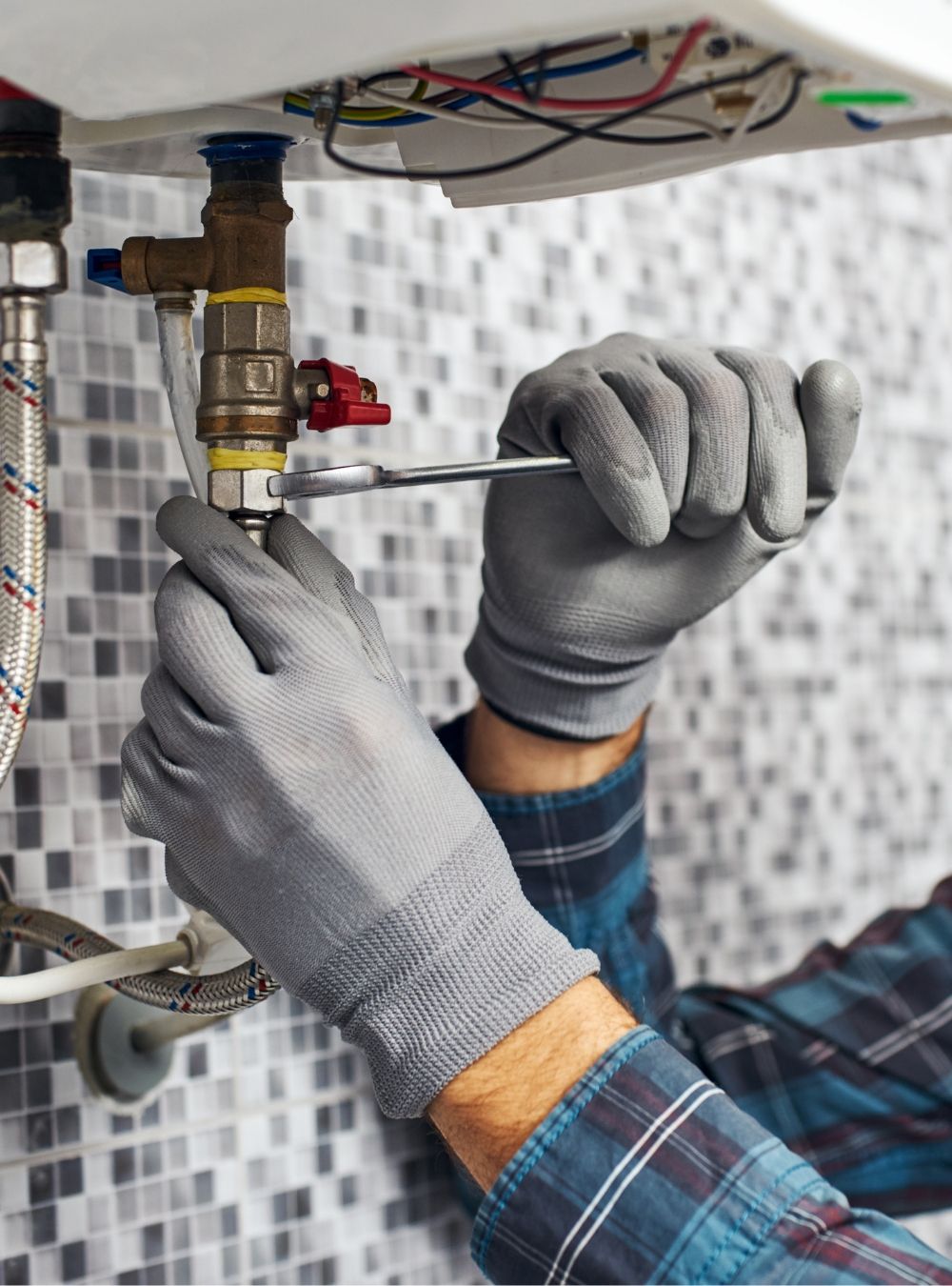 Gloved plumber hands working on a water heater connection