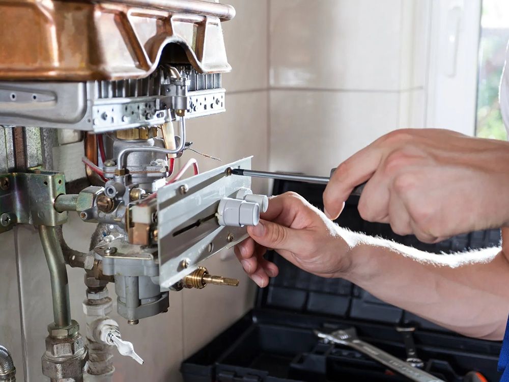 Hands with tools working on a water heater