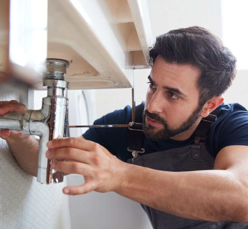 A plumber installing pipes under a sink