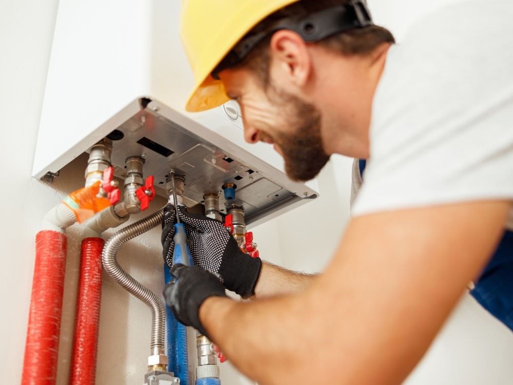 A plumber looking at a water heater's pipes