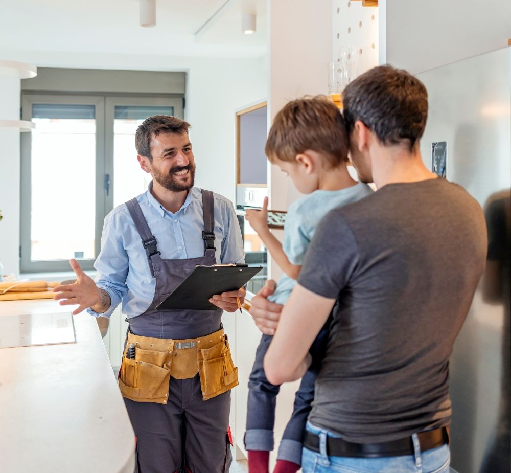 A plumber talking with a client in their kitchen