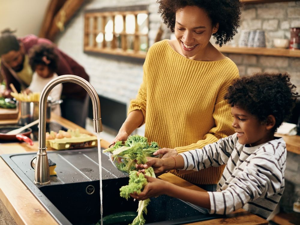 A mother and son cleaning vegetables in the sink