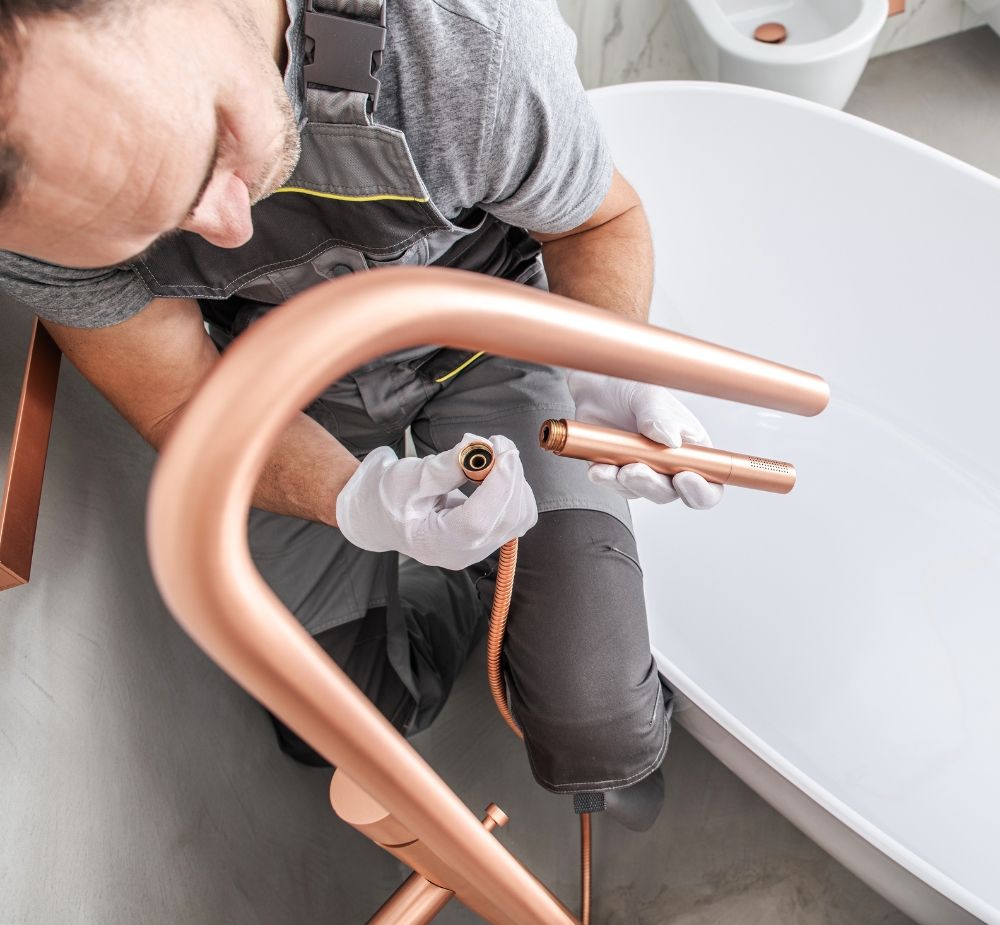 A plumber installing a tub faucet