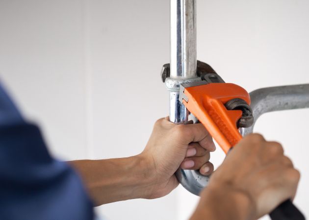 A plumber with a wrench working on a pipe