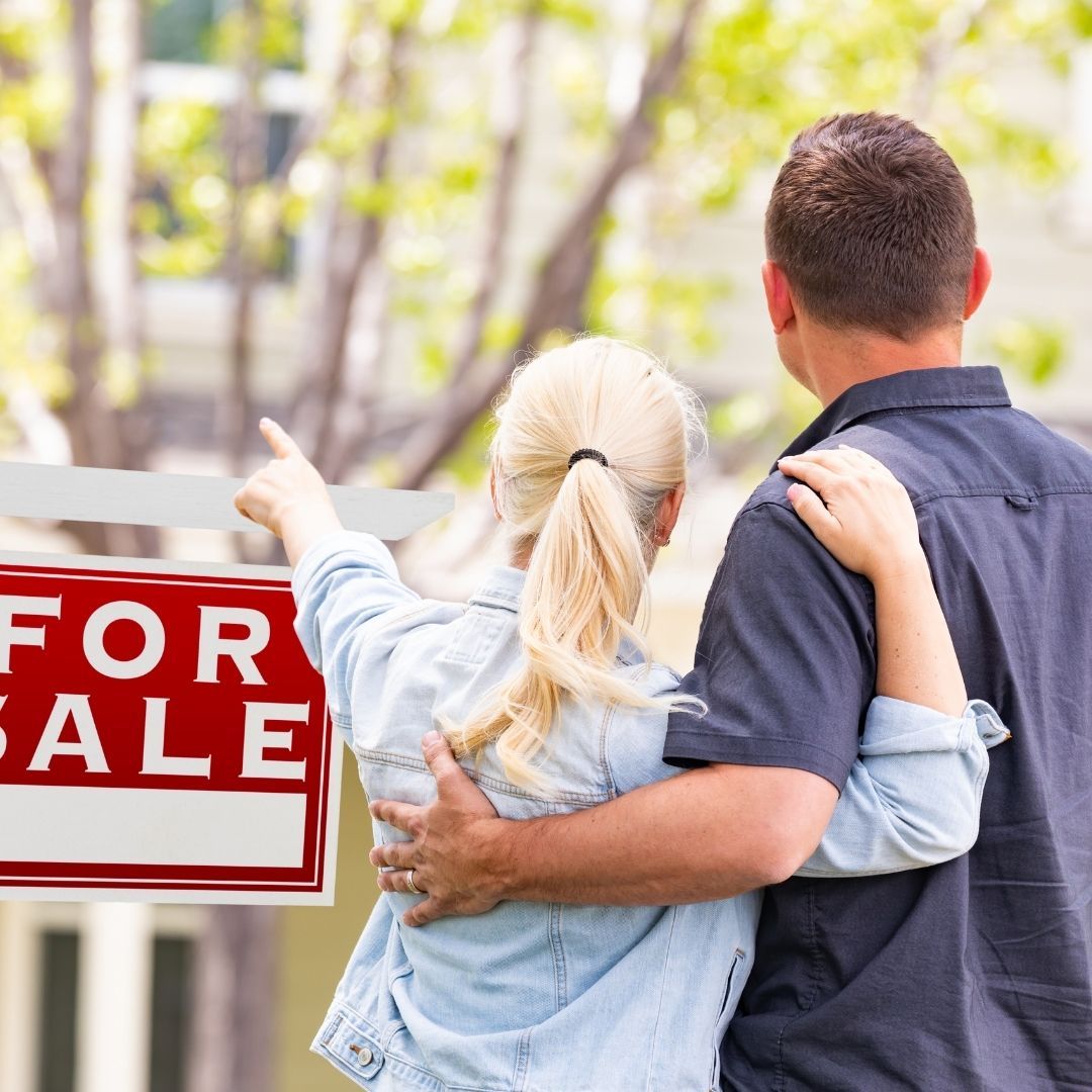 A couple in front of a for sale sign