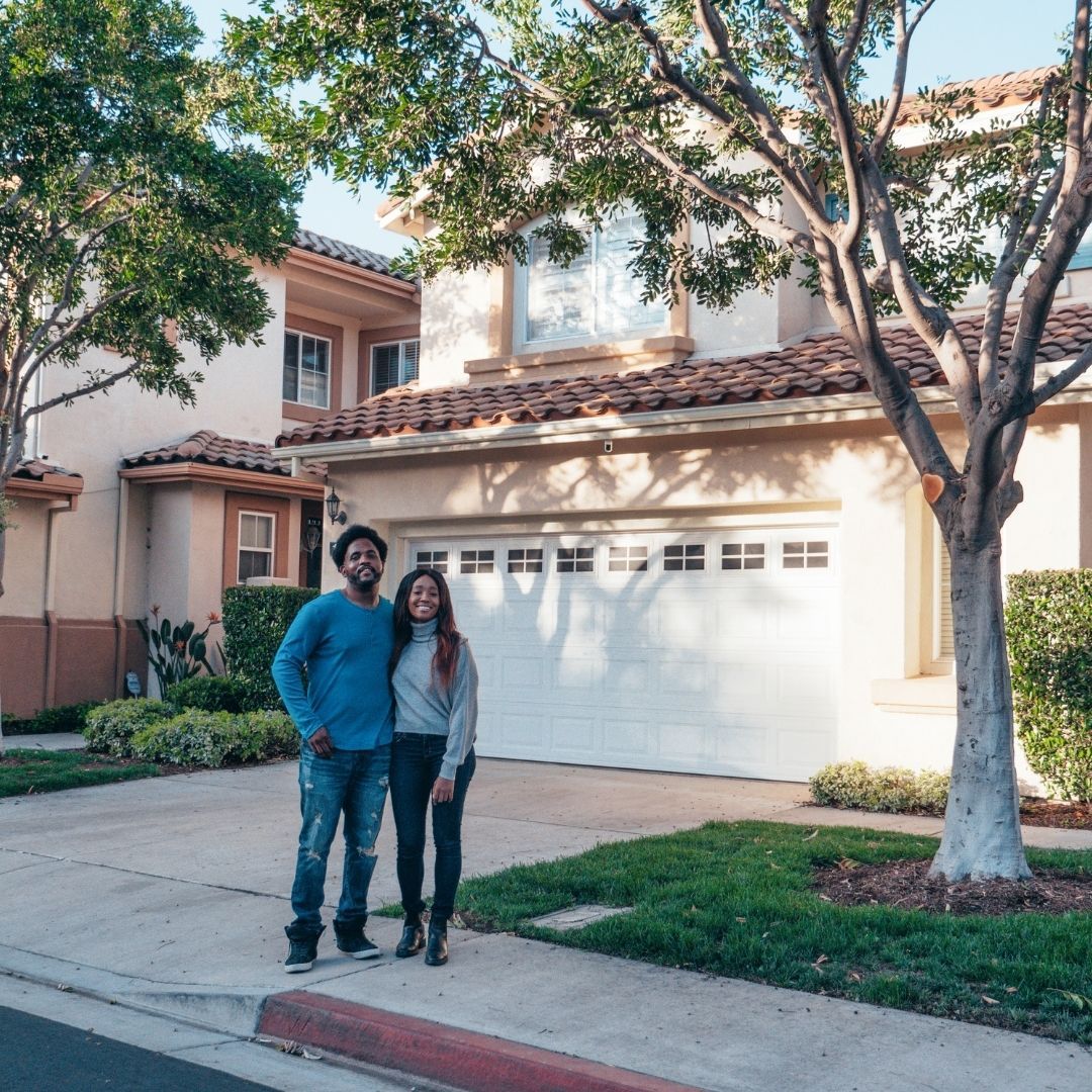 young couple in front of a home