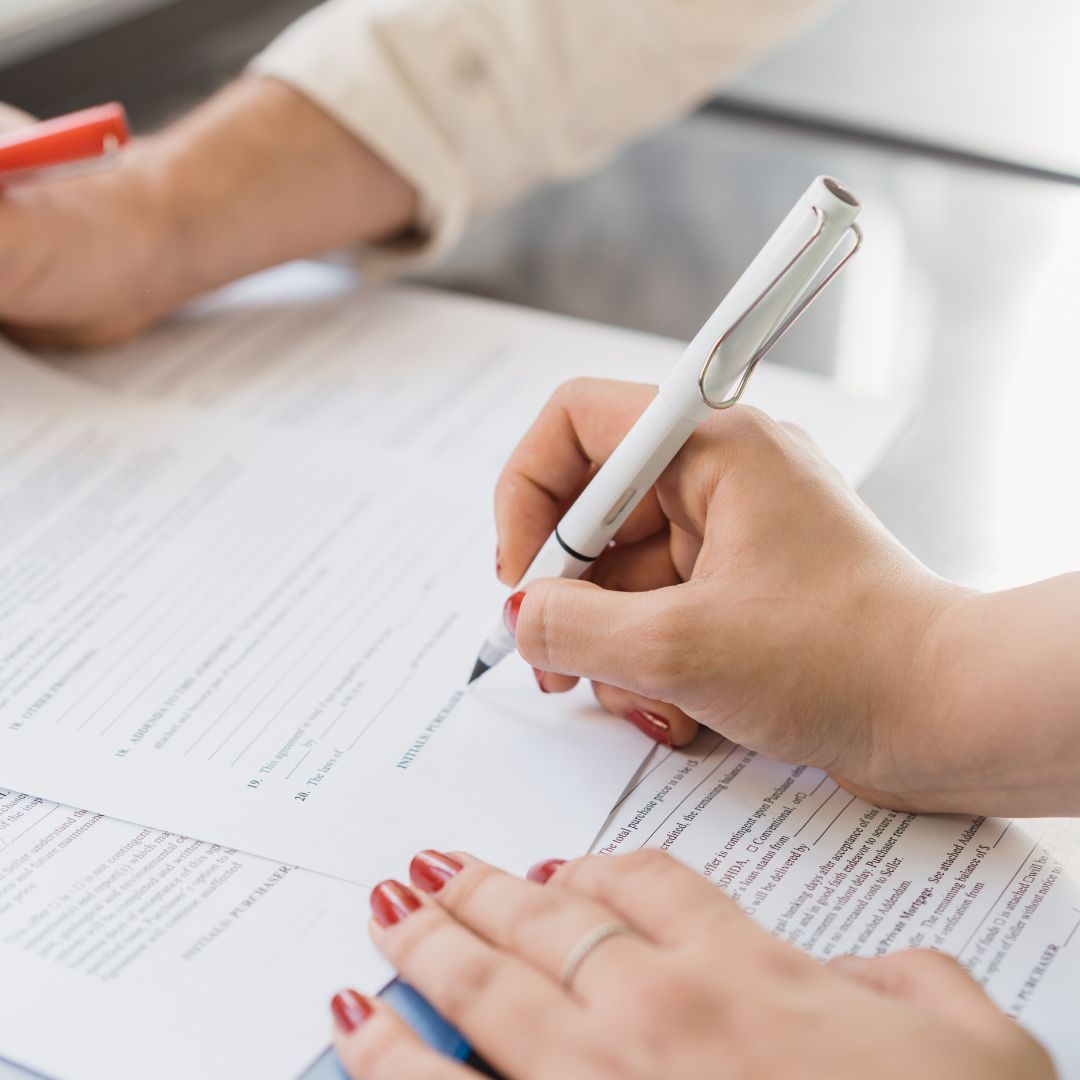 hand holding a pen signing paperwork