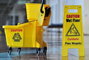 Commercial mopping bucket next to a wet floor sign