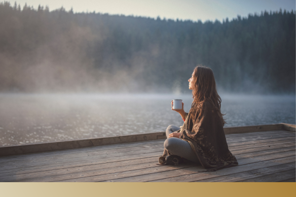 woman sitting on a dock with a cup of coffee. 